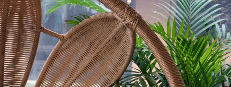 Detalhe de cadeira de fibra sintética em ambiente decorado com plantas e luz natural, representando a ideia de decoração sensorial e bem-estar.